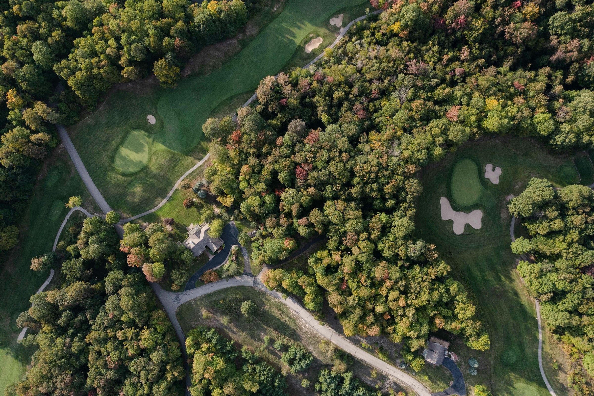 Vue du parcours au soir, fairway serpentant entre les bois