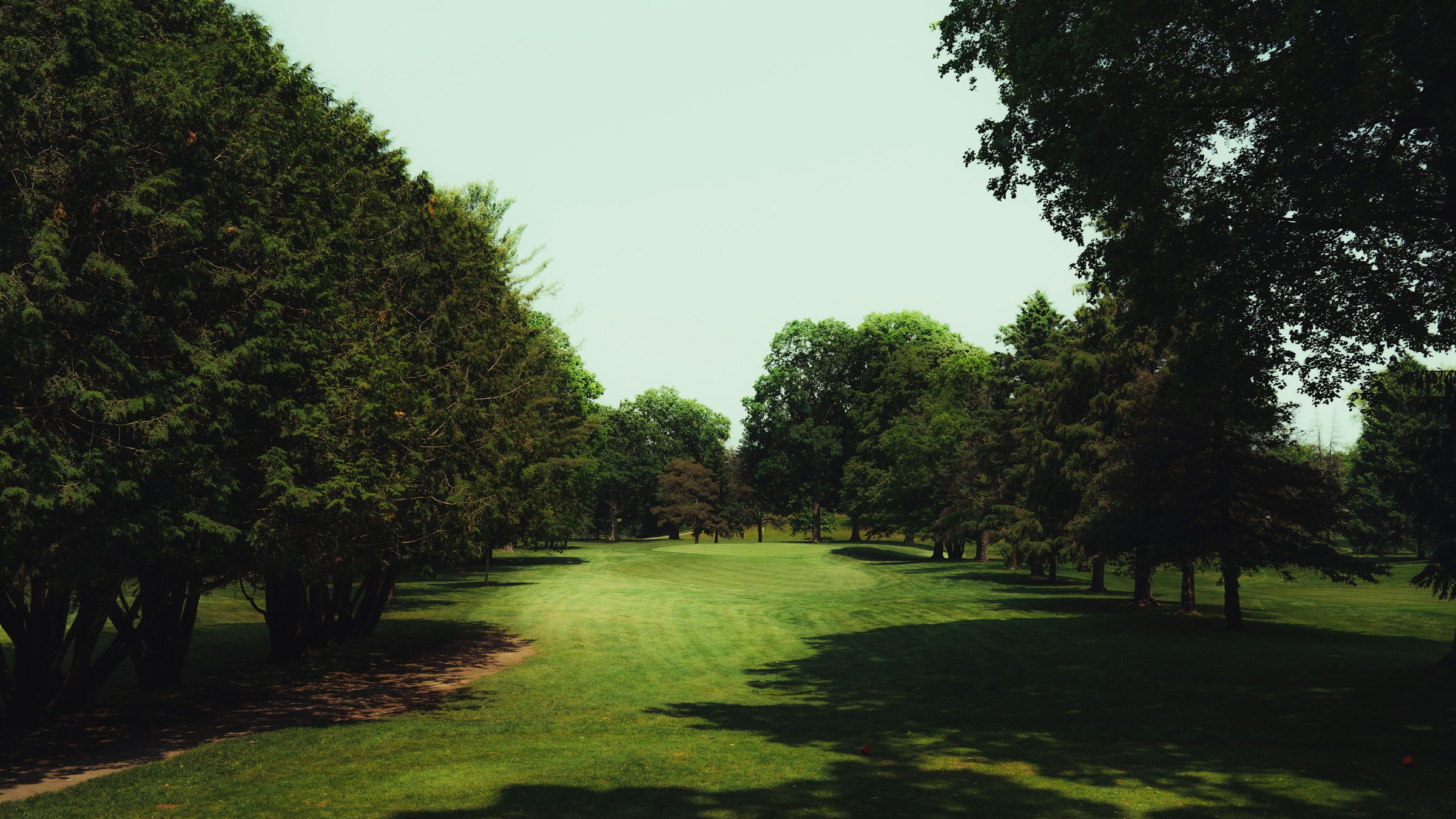 Le couloir boisé du trou 9, fairway remontant vers le club-house
