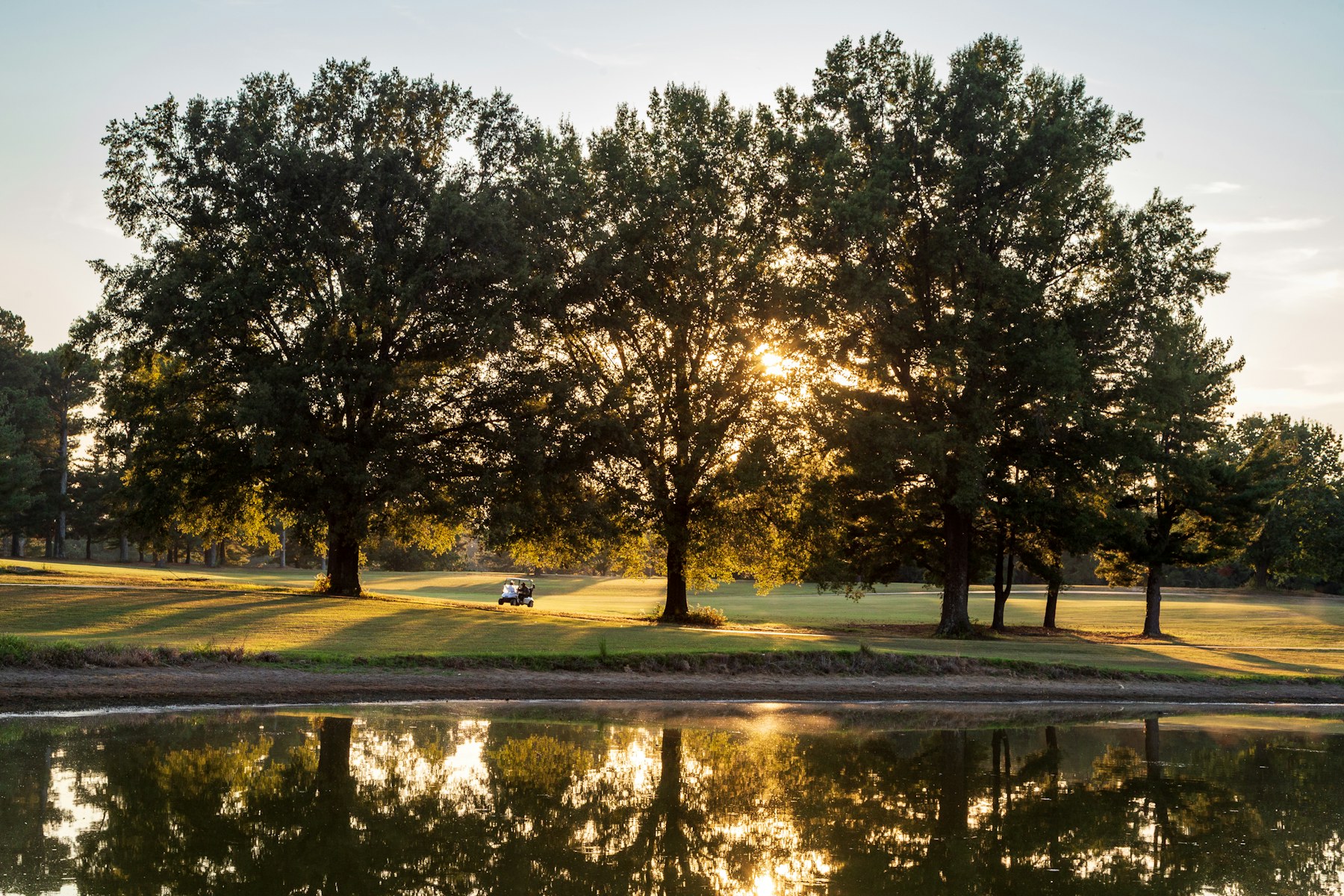 Le plan d'eau du trou 17 à droite du fairway, reflets d'arbres dans la lumière du soir